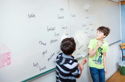 Schoolboys learning spellings on whiteboard in classroom